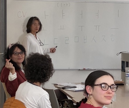 Yong Hee Cho au tableau, écrivant les voyelles et consonnes du hangeul devant ses élèves.