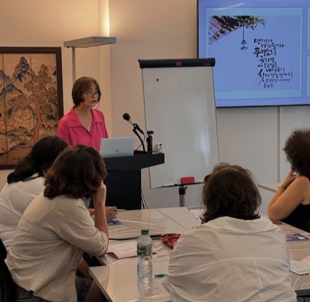 Yong Hee Cho présentant la calligraphie coréenne devant un petit groupe.